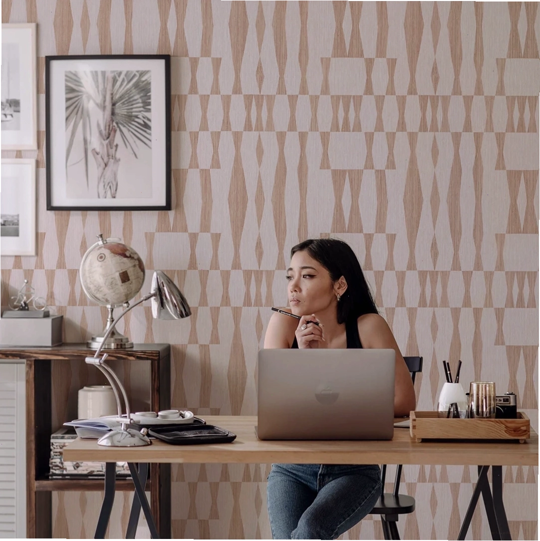 College student at a desk with neutral faux grasscloth wallpaper
